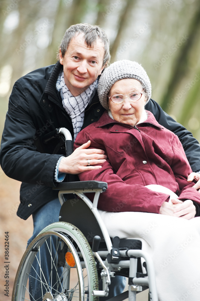 old senior woman in wheelchair with careful son old senior woman in wheelchair with careful son