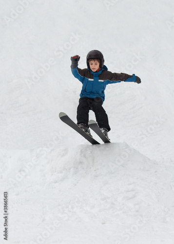 Little boy jumping on snow skis