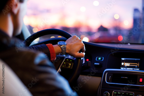 Billede på lærred Driving a car at night - young man driving her car