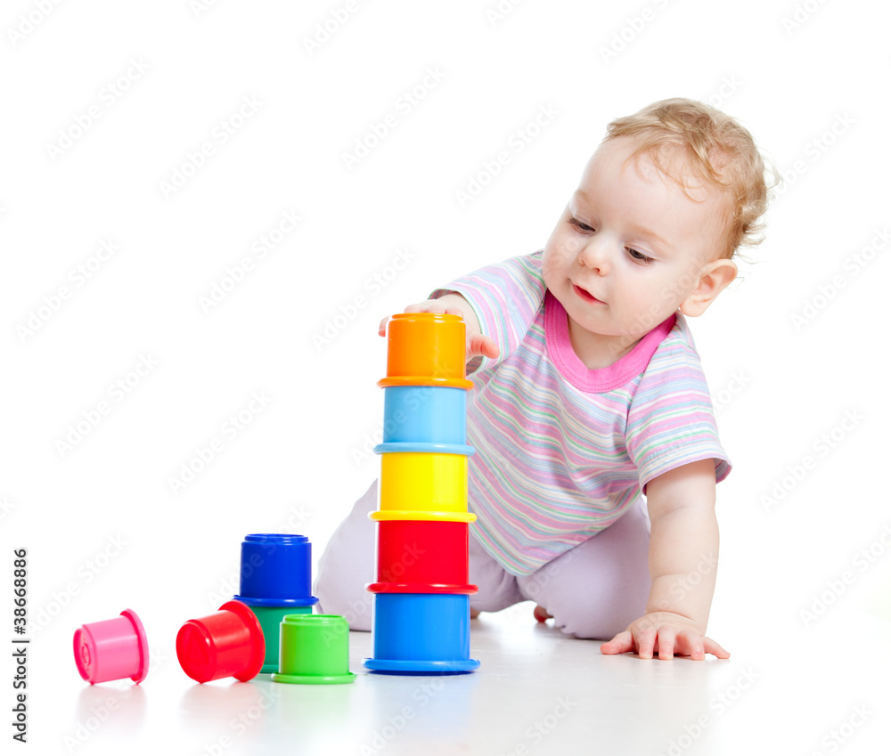 Cute little boy building tower from colorful cups isolated on wh Cute little boy building tower from colorful cups isolated on wh