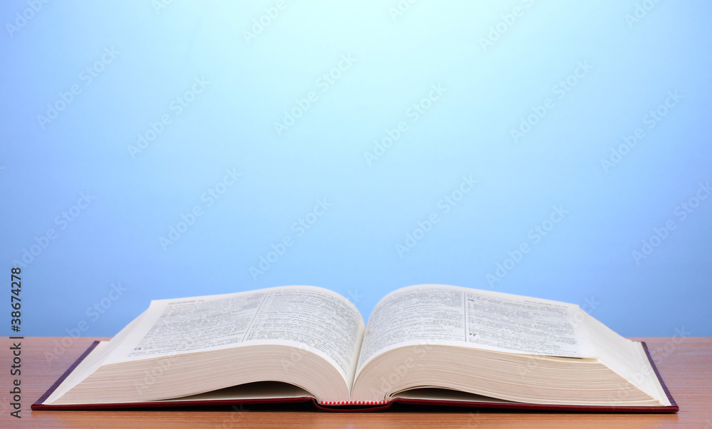 Open book on wooden table on blue background Open book on wooden table on blue background