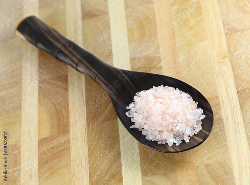 Photography Bolivian Rose salt in a wooden spoon on a wooden table.