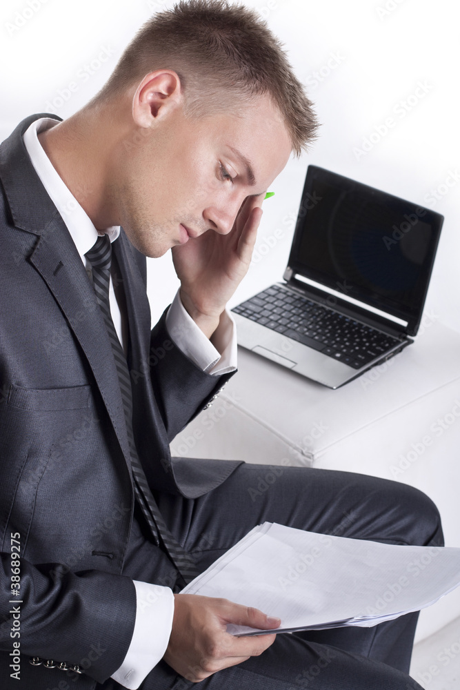 Stressed businessman sitting at desk holding his head and worryi Stressed businessman sitting at desk holding his head and worryi