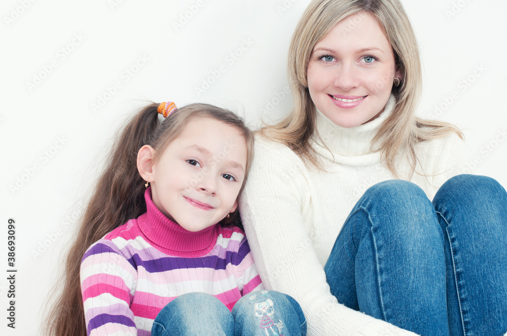Little girl and her mother sitting by each other on the floor