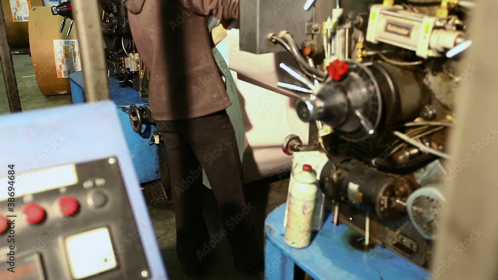 Set up new paper roll on press machine in a print shop Set up new paper roll on press machine in a print shop