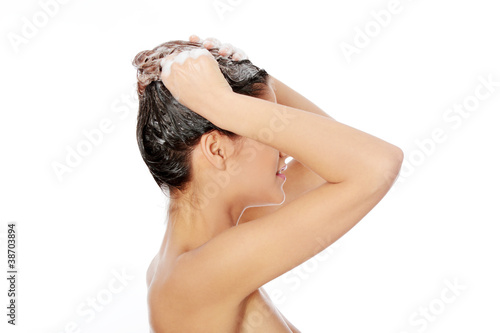 Beautiful young woman washing her hair with shampoo