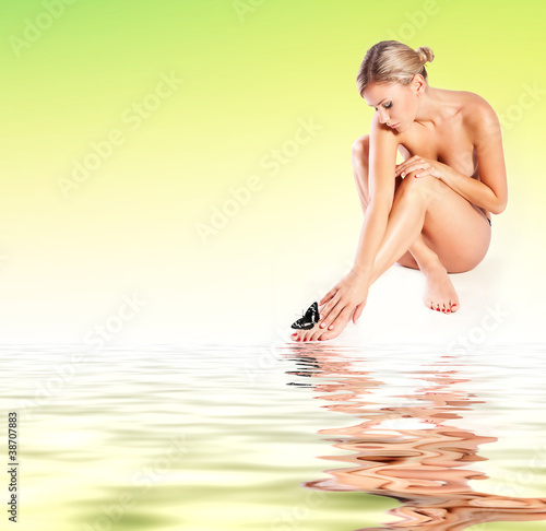 Young woman with butterfly and reflection on a water surface