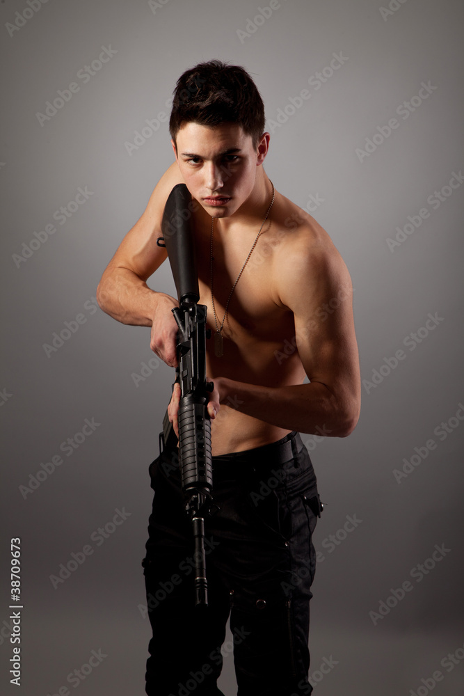 Handsome bare-chested soldier is holding a rifle Handsome bare-chested soldier is holding a rifle