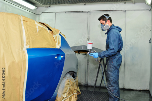 Worker painting a blue car.