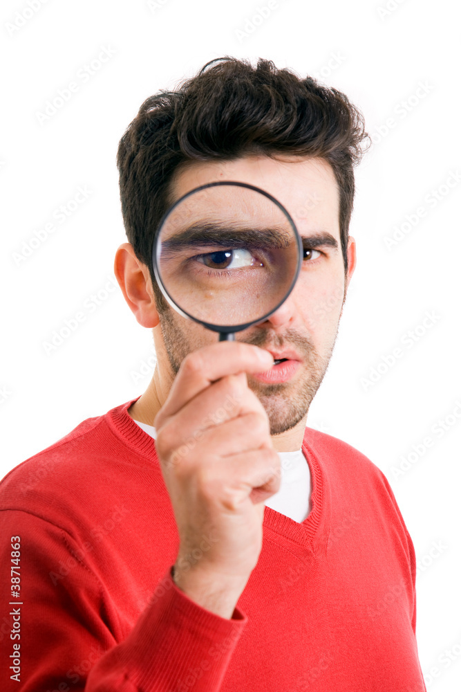 Portrait of young man looking through a magnifying glass over wh Portrait of young man looking through a magnifying glass over wh