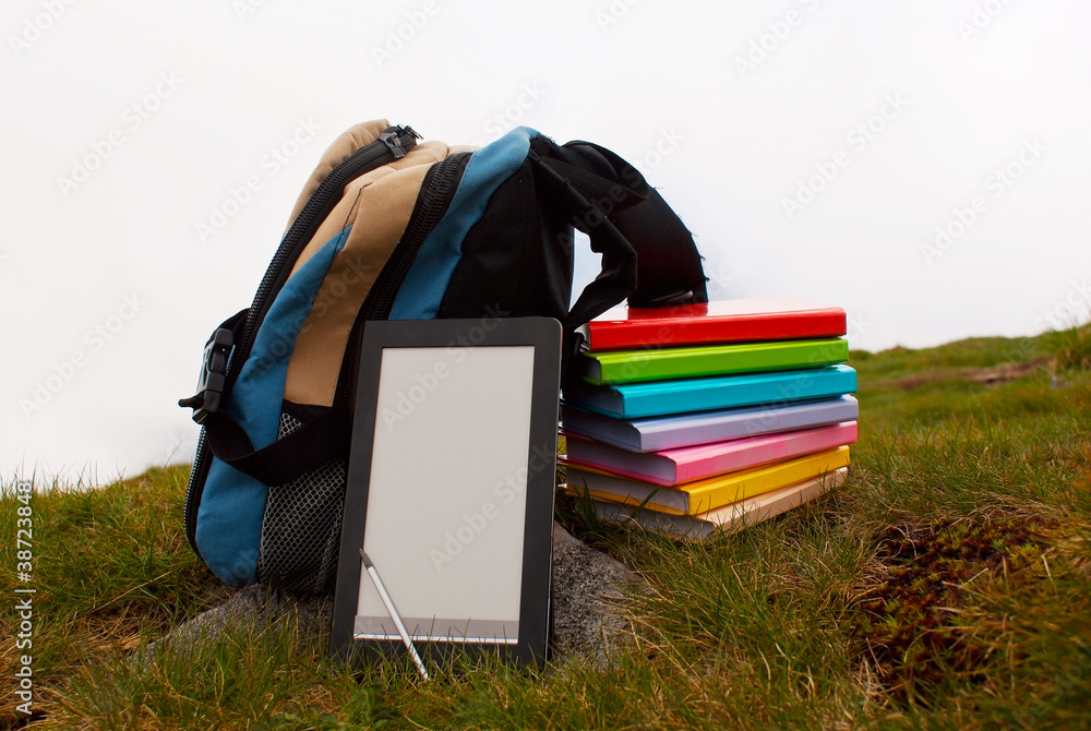 Stack of colorful books and electronic book reader