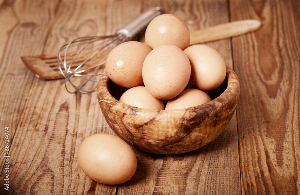 fresh brown eggs with egg whisk on wooden background fresh brown eggs with egg whisk on wooden background