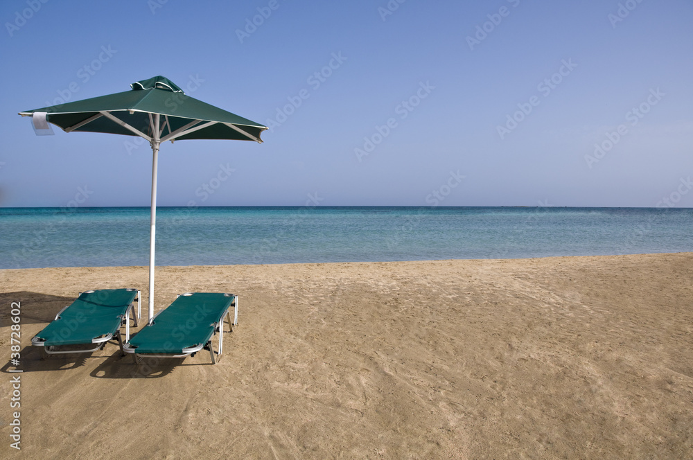 Sunny beach with umbrella and beach chairs