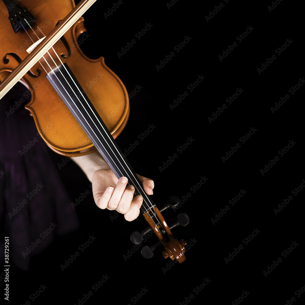 Fototapeta premium Young girl practicing the violin. Over black background.