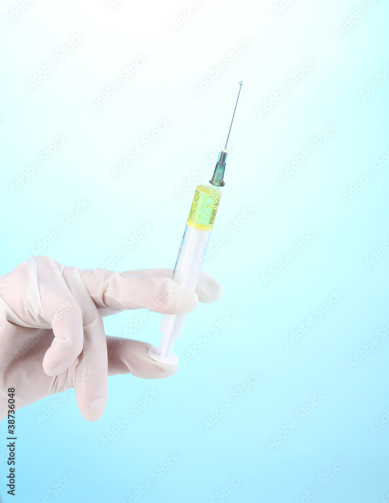 Syringe in hand on blue background Syringe in hand on blue background