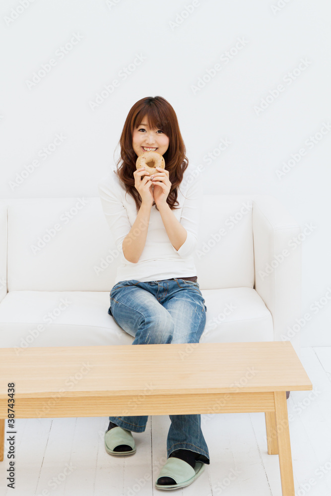 Beautiful young woman eating a bagle