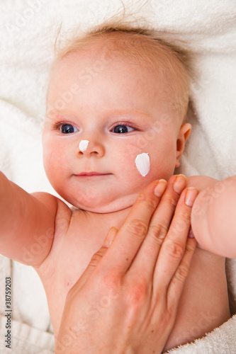 Mother creaming cute infant girl face
