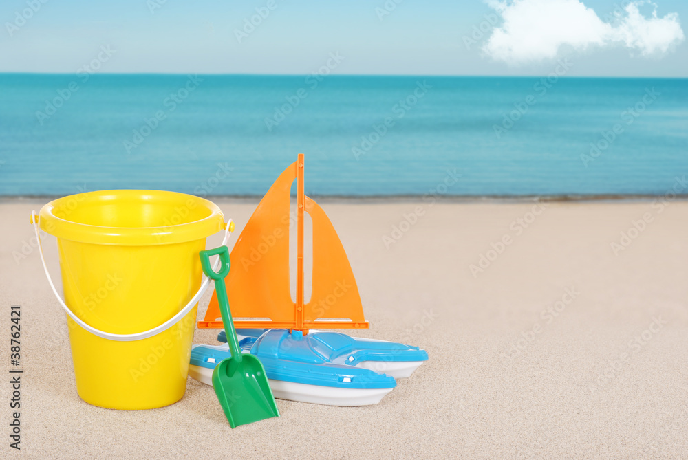 Toy Sailboat and childs bucket on the beach Toy Sailboat and childs bucket on the beach