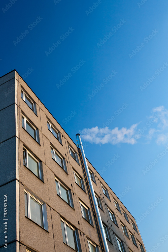 smoke/flue gases going out of a chimney by an apartment building