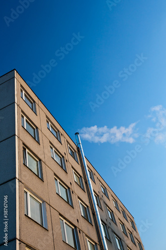 smoke/flue gases going out of a chimney by an apartment building