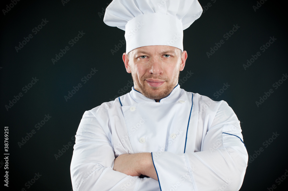 Chef in uniform with his arms crossed, over dark background Chef in uniform with his arms crossed, over dark background