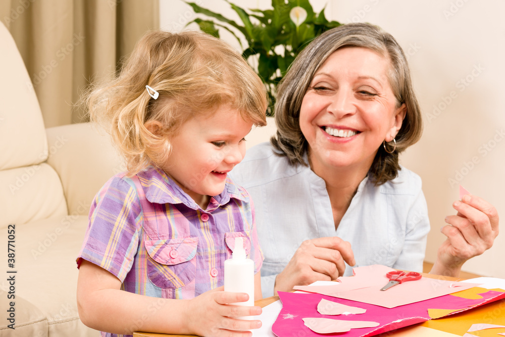 Little girl with grandmother play glue paper Little girl with grandmother play glue paper