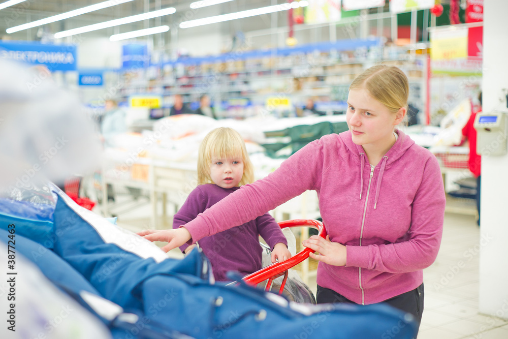 Mother and daughter look pillows in supermarket