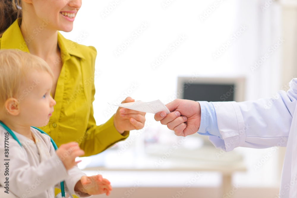 Closeup on pediatric doctors hand giving prescription to mother Closeup on pediatric doctors hand giving prescription to mother