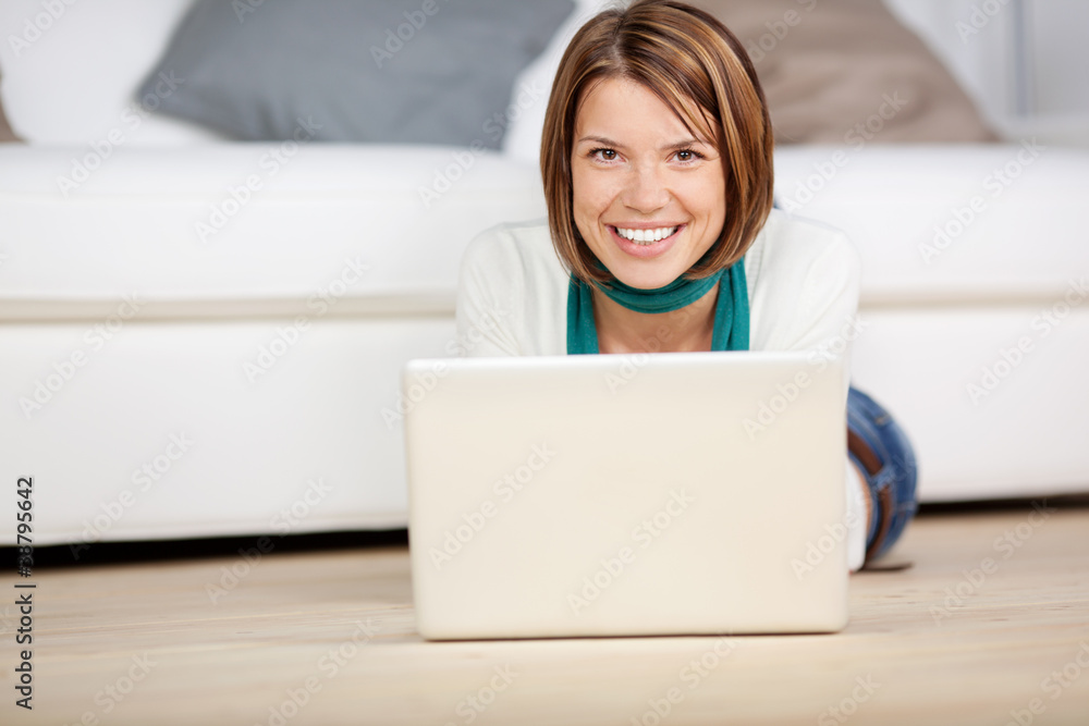 lächelnde junge frau mit laptop im wohnzimmer lächelnde junge frau mit laptop im wohnzimmer