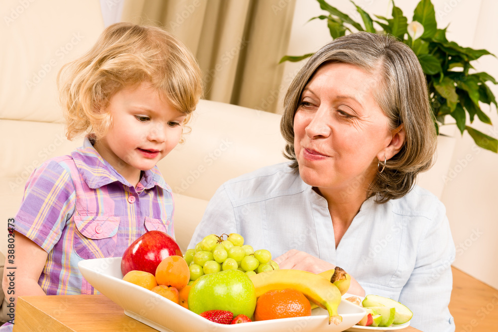 Grandmother with granddaughter eat fruit at home Grandmother with granddaughter eat fruit at home