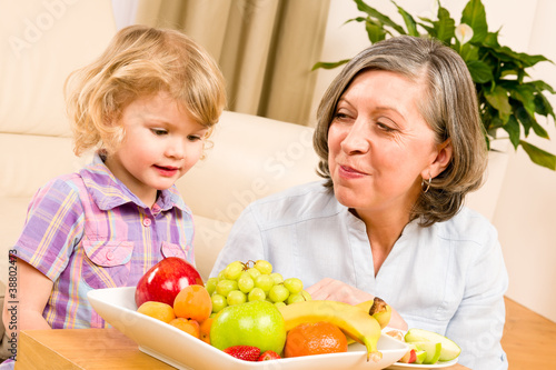 Grandmother with granddaughter eat fruit at home © CandyBox Images