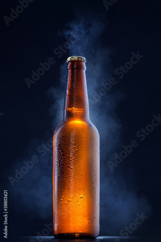 Cold beer bottle with drops  frost and vapour on black