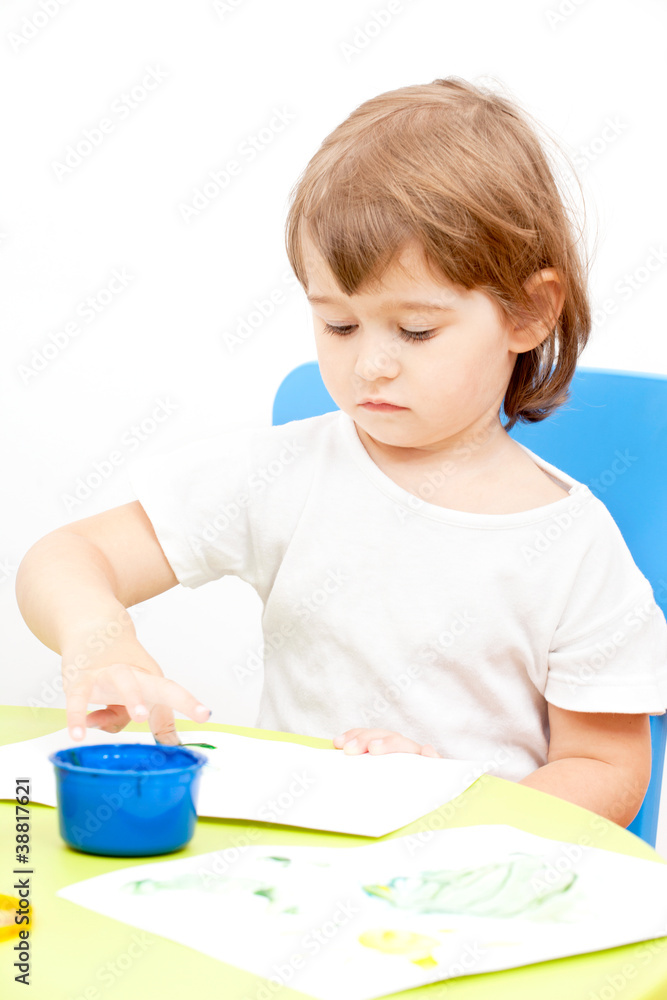 ittle girl draws paint sitting at the table ittle girl draws paint sitting at the table