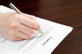 Male hand filling out and signing contract