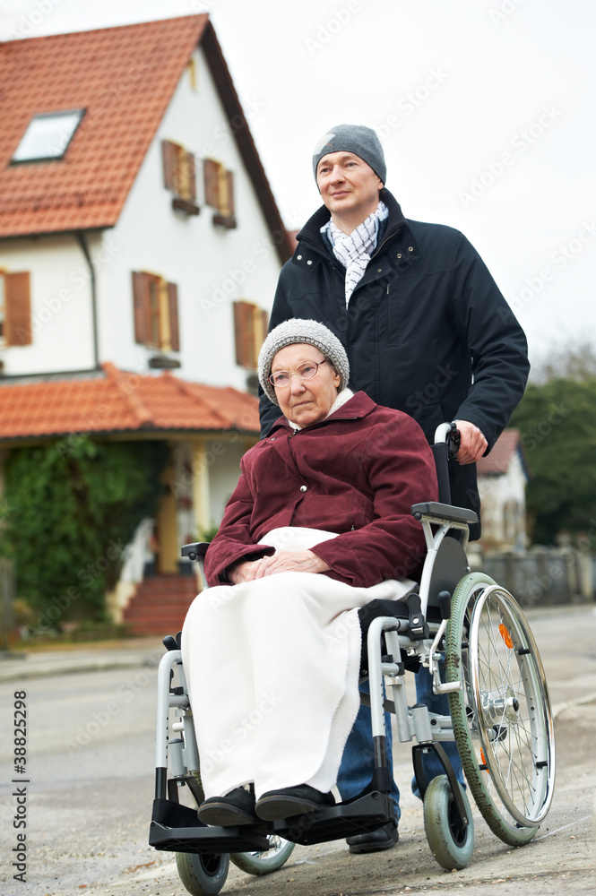 old senior woman in wheelchair with careful son