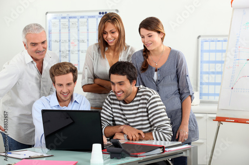 Co-workers gathered around computer screen