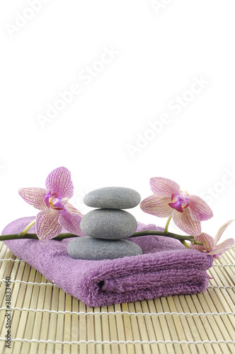 pink towel and stones and orchid on bamboo mat