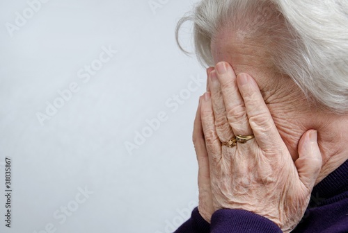 A crying elderly woman covering her face