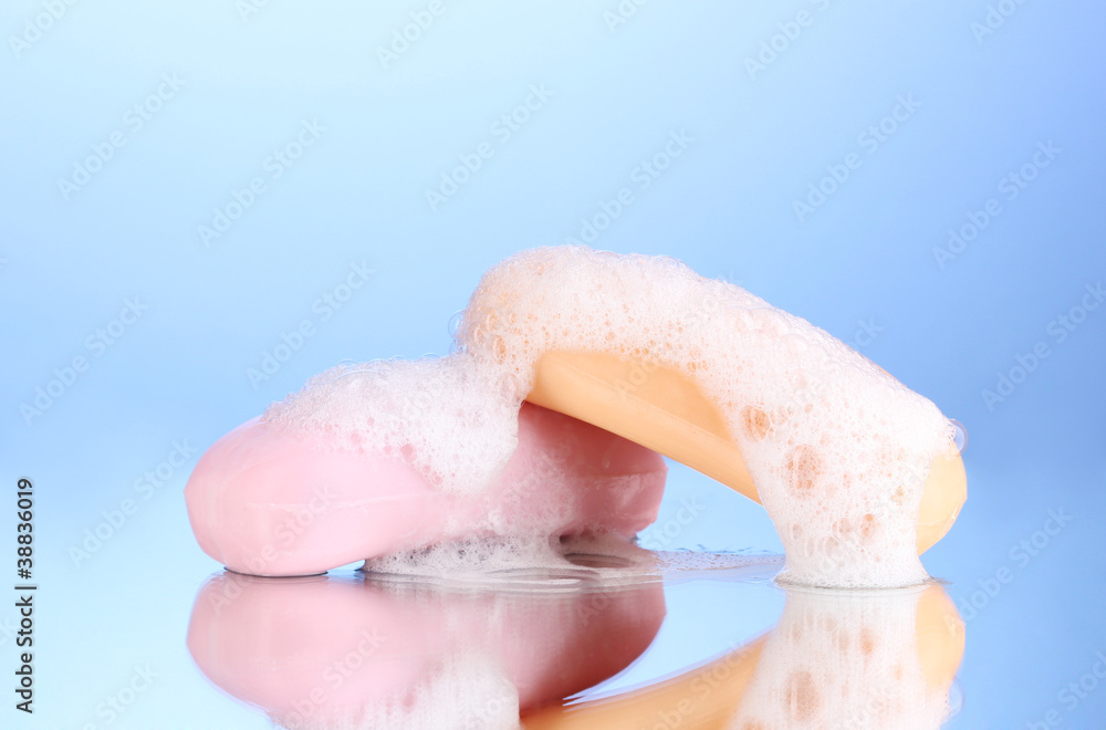 Two soaps with foam on blue background