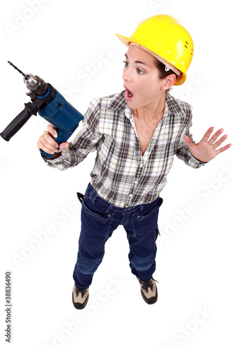 A scared female construction worker with a drill.