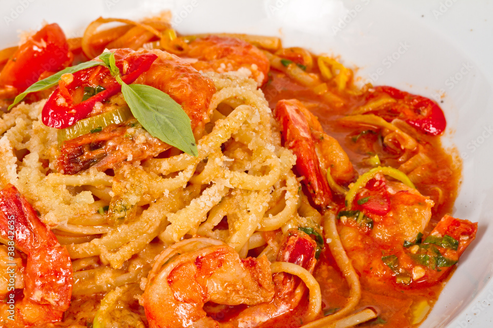 A plate of linguini with sauteed shrimp, tomato, chili  and oliv