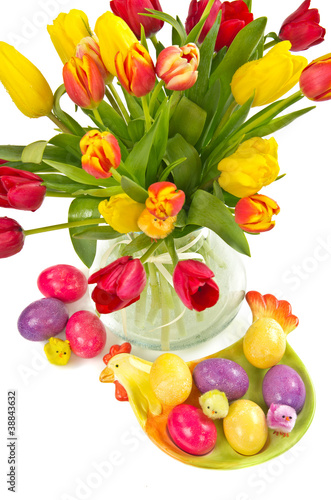 Easter eggs on plate and colorful tulips over white