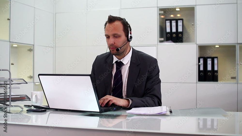 Young helpdesk consultant talking on headset in modern office Young helpdesk consultant talking on headset in modern office