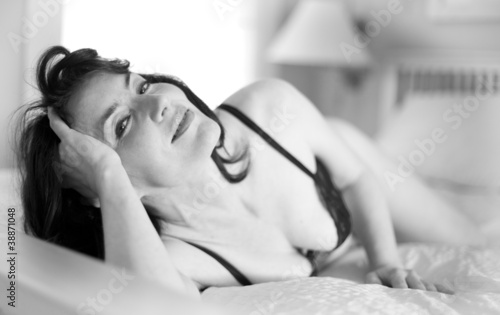 Sexy middle-aged woman in lingerie, lying in bed
