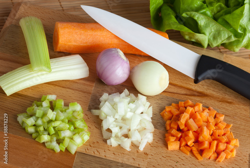 Sedano, cipolle e carote tagliate con coltello di ceramica photo