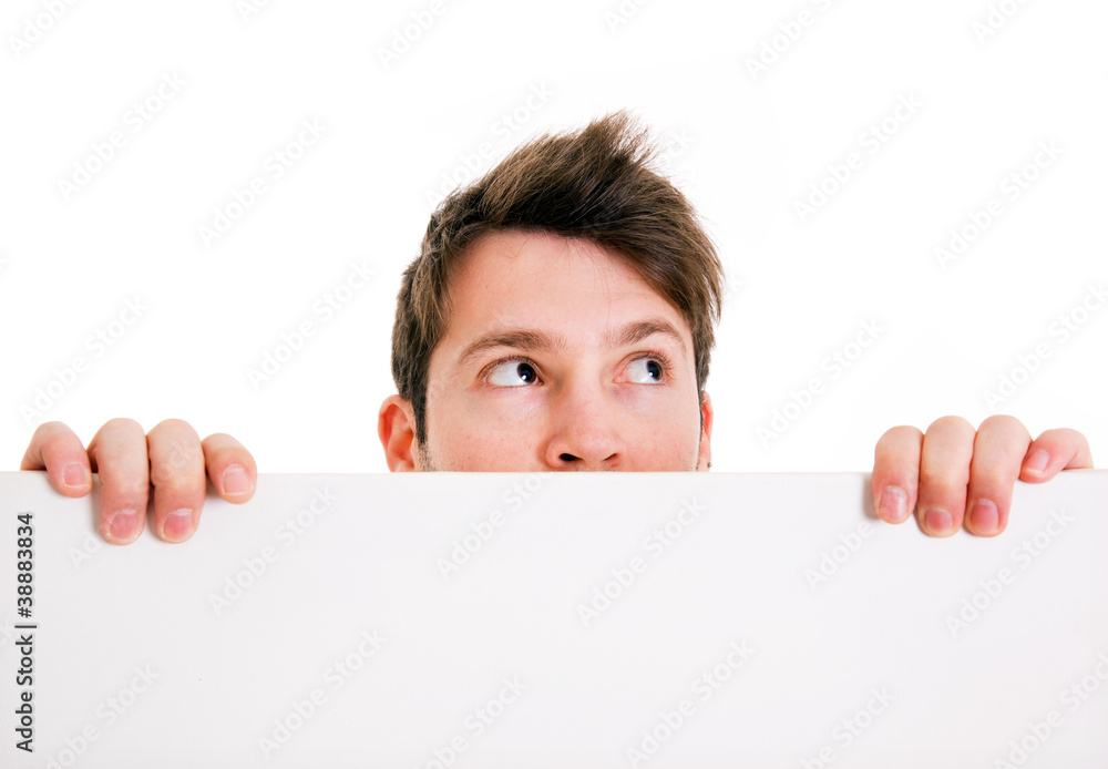 Young man holding a blank white board and looks at the corner Young man holding a blank white board and looks at the corner