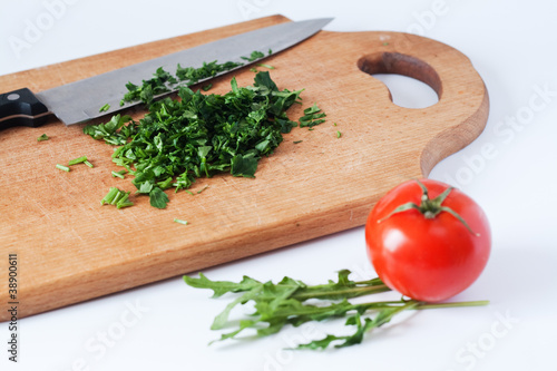 Chopped fresh herbs, a knife, wooden boards, and red tomato