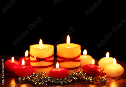 Beautiful candles and decor on wooden table on black background
