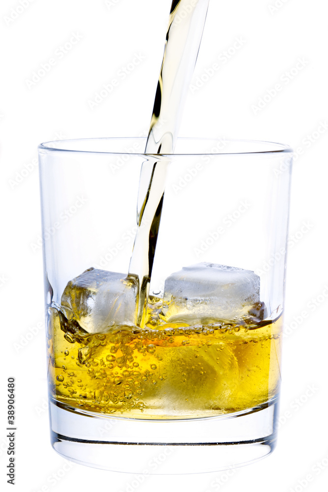 Whiskey pouring into a glass isolated on white