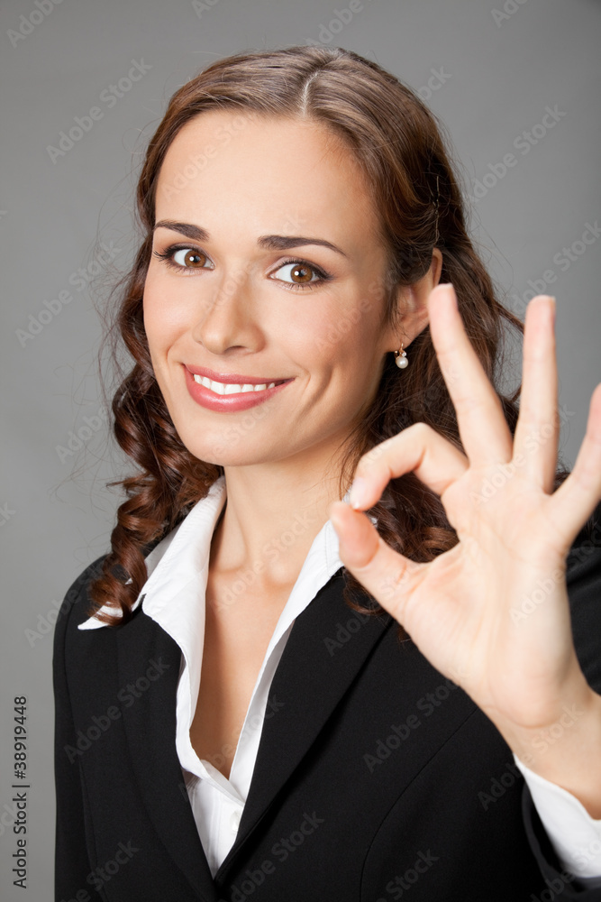 Happy business woman with okay gesture, over grey Happy business woman with okay gesture, over grey